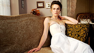 woman in white tube dress sit on brown floral sofa